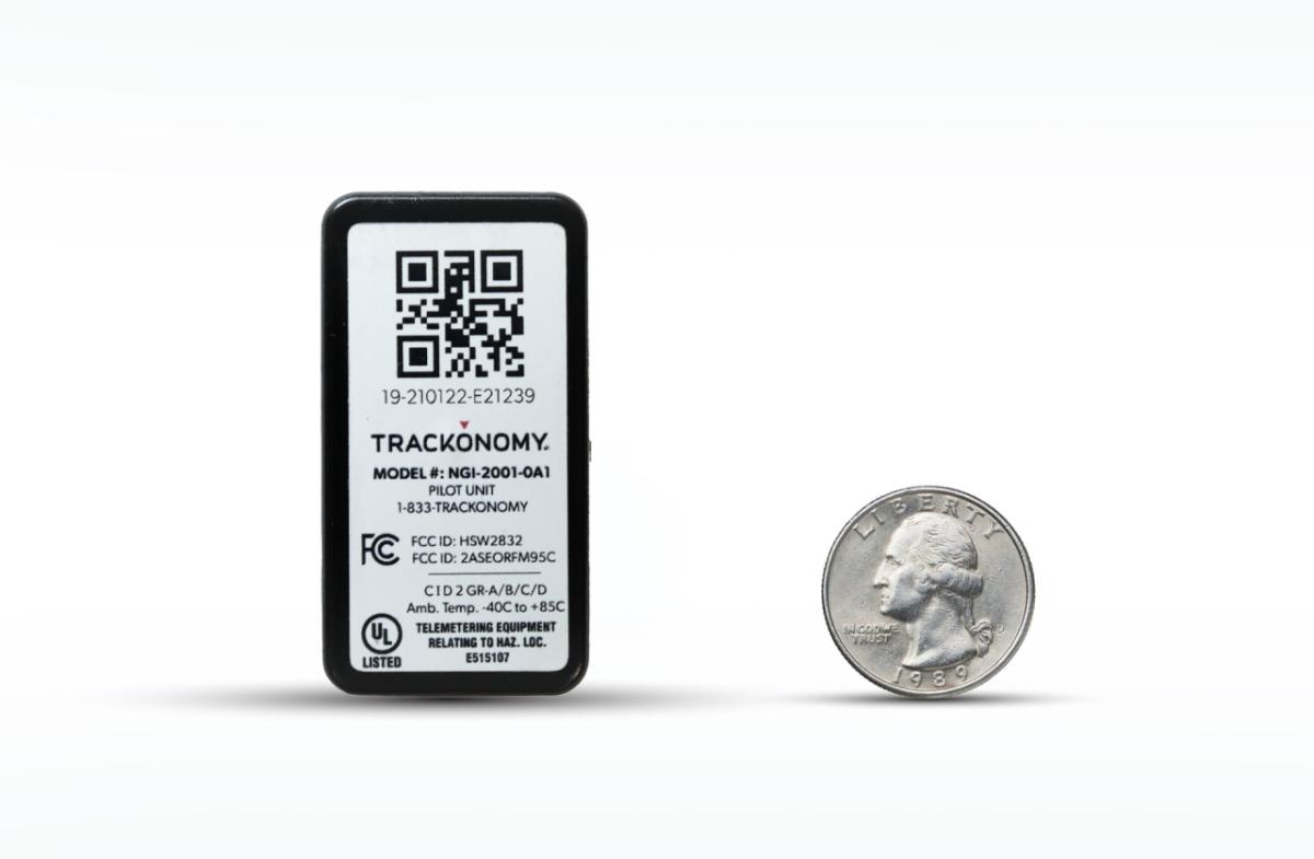 A compact Trackonomy industrial sensing device shown beside a quarter for scale