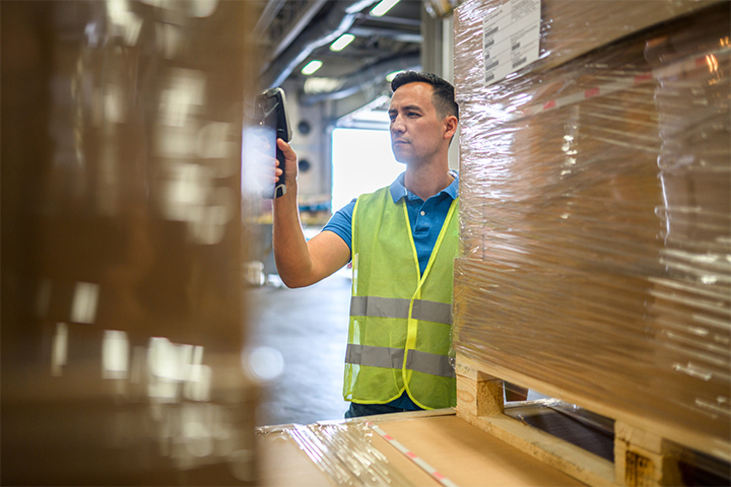 Warehouse worker scanning stock between pallets, an investor case-study illustration