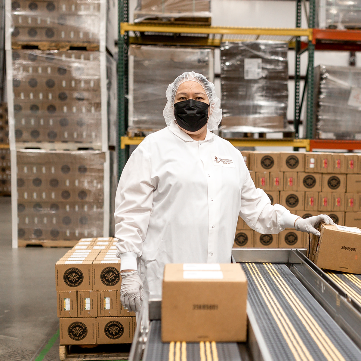 Traditional Medicinals team member beside packed tea cartons in the company’s operations area