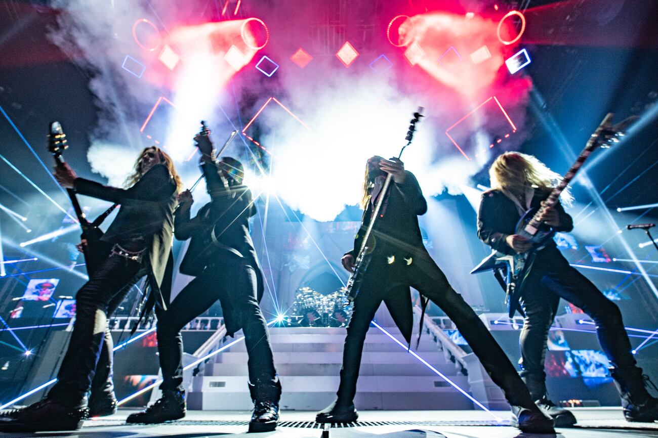 Four Trans-Siberian Orchestra musicians perform beneath red light, lasers and stage smoke