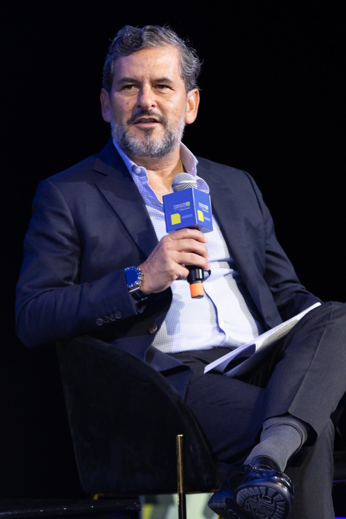 A Movantis executive speaking into a microphone during a conference panel