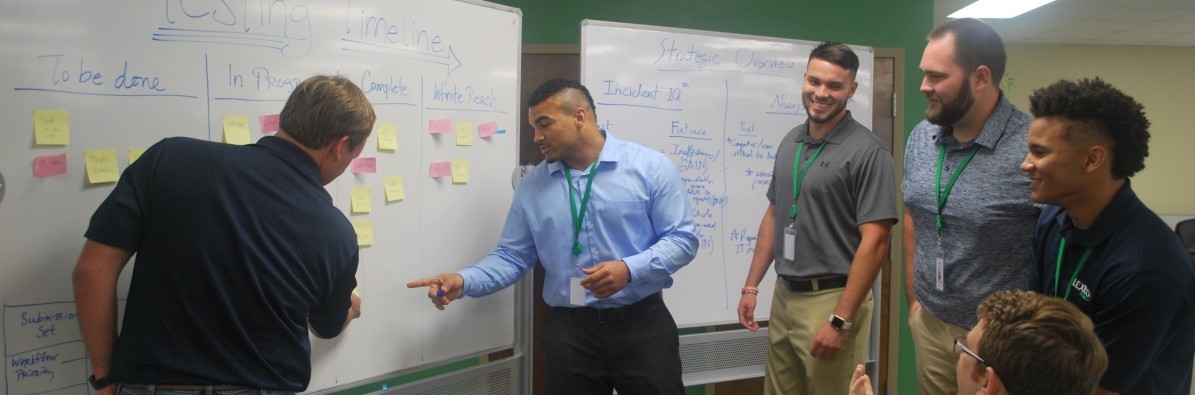 The Lexicon team and Georgia Tech interns discussing work beside whiteboards in 2017