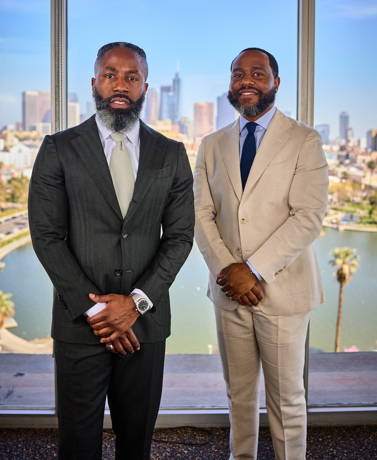 Rodney Williams and Travis Holoway in suits, standing together in front of the Los Angeles skyline