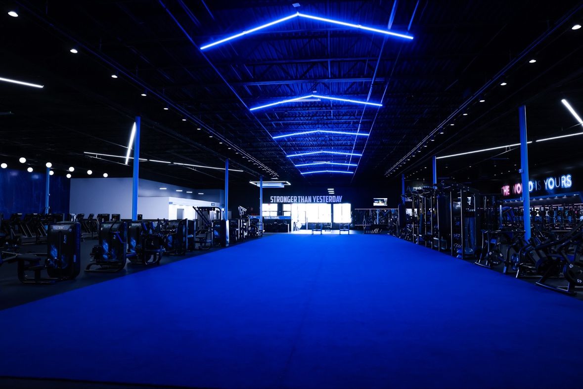 Daytona gym floor with blue turf, dark equipment and geometric blue ceiling lights