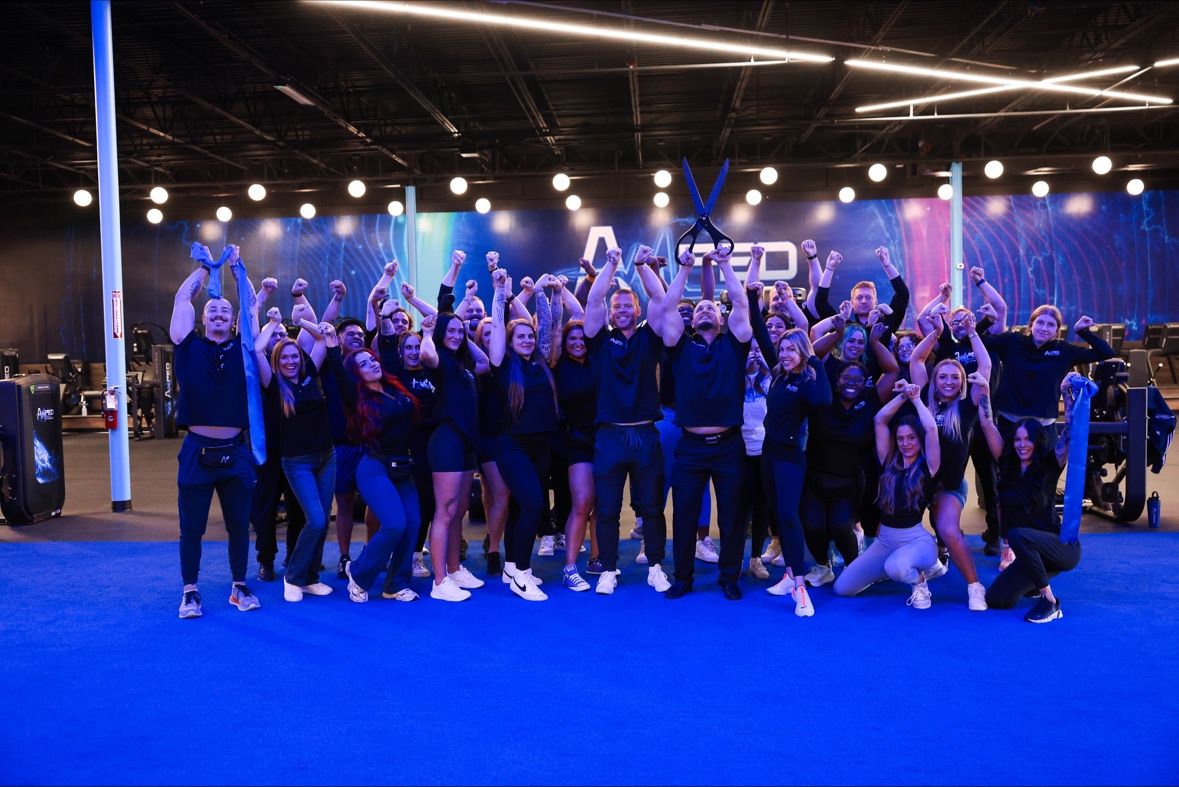 Amped Fitness team celebrating together on the blue gym floor in Daytona