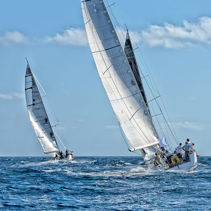 Two racing sailboats leaning into the wind on open water