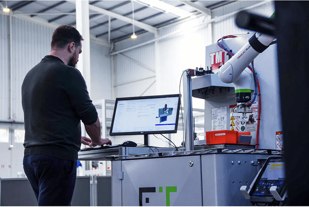 Operator at a Trener Acteris machine tending cell with a collaborative robot