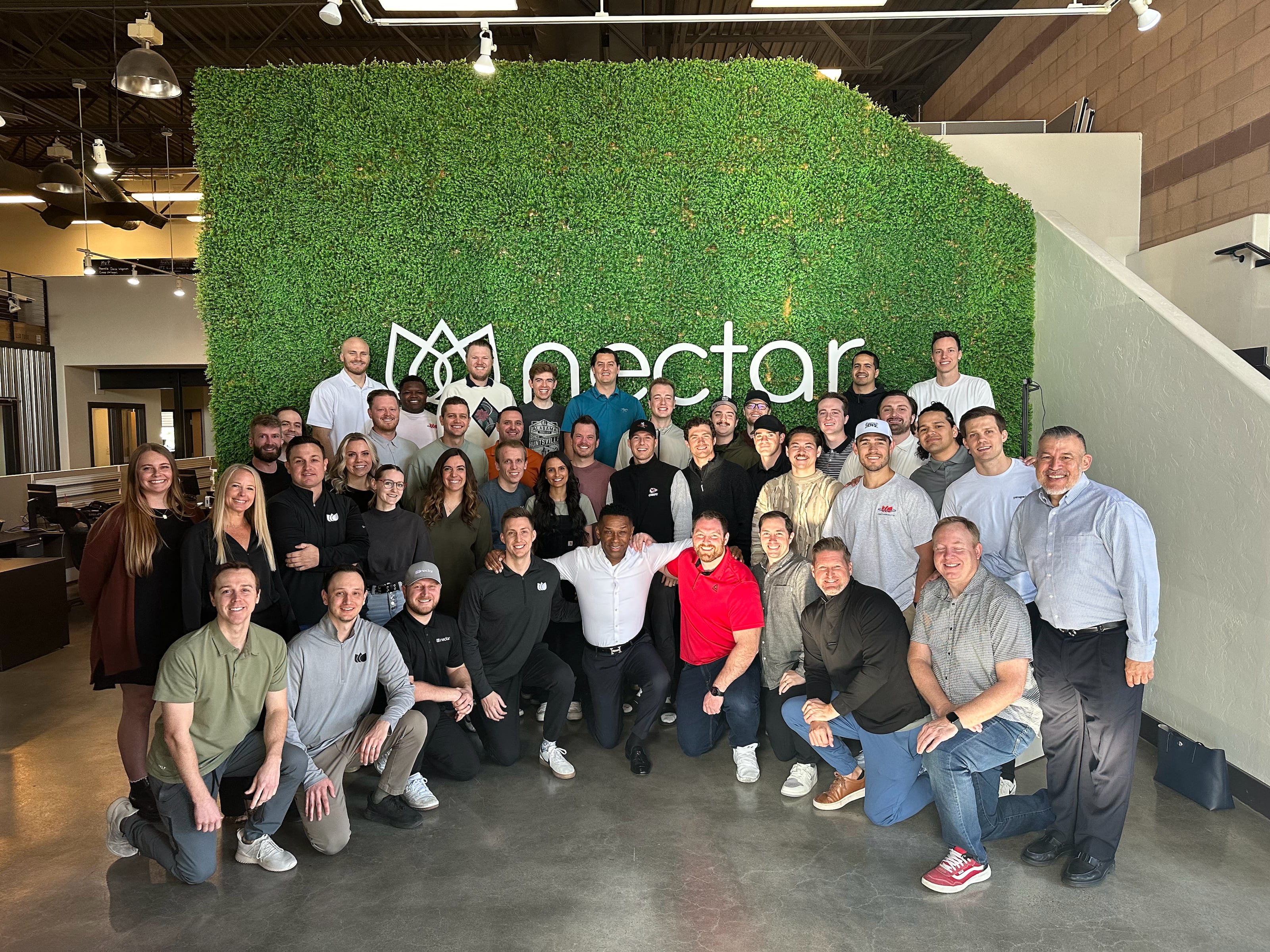 The Nectar team gathered with SHRM CEO Johnny C. Taylor Jr. in front of a green Nectar wall