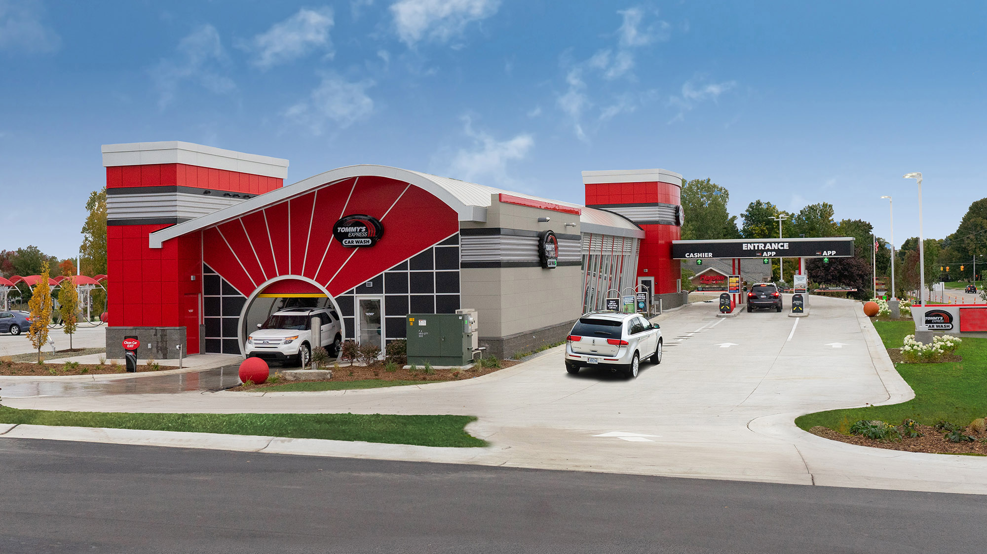 Tommy’s Express car wash with red towers, glass walls and separate customer entry lanes