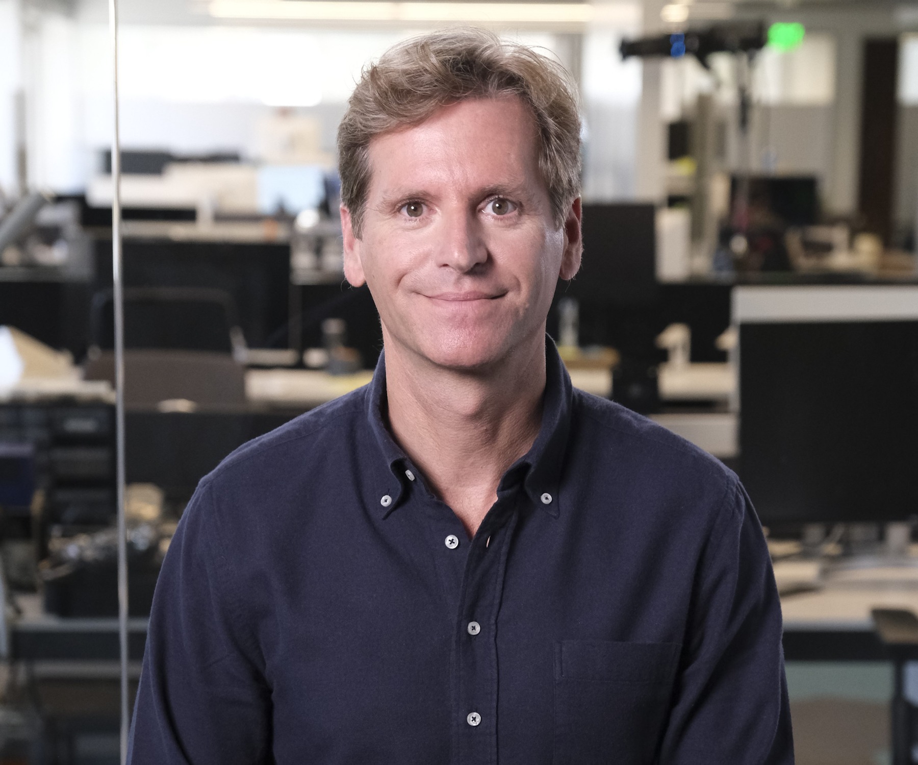 Trevor Traina in an office with glass partitions and desks