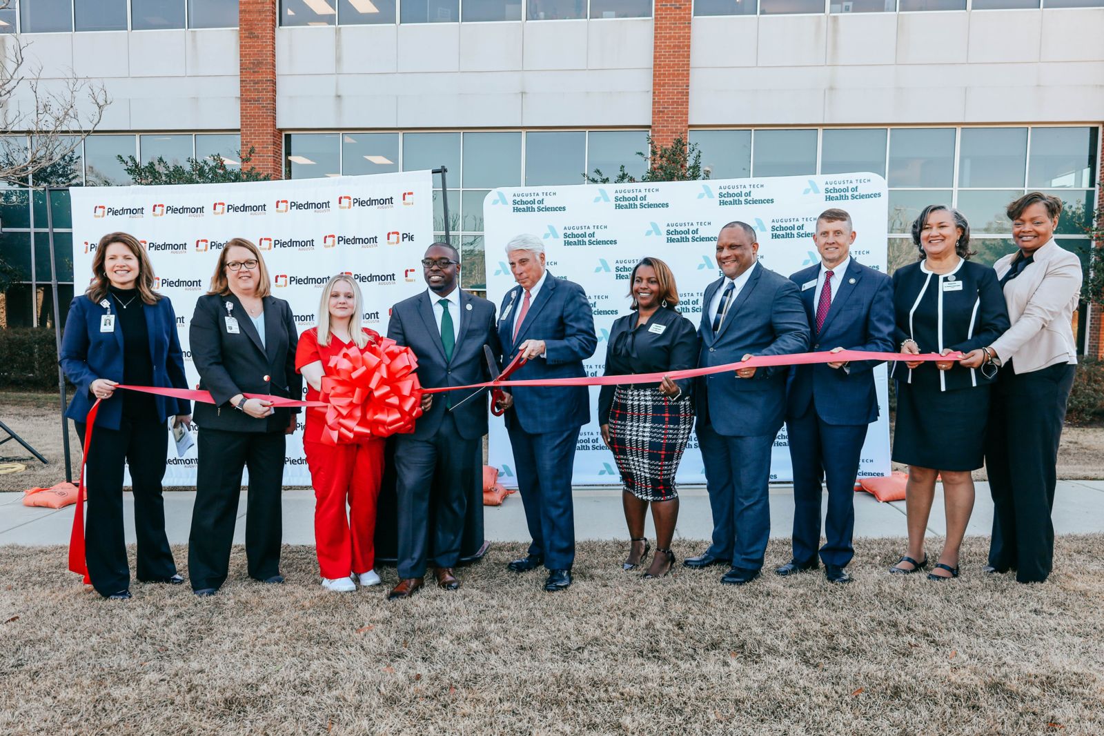 Augusta Technical College and Piedmont leaders cut a red ribbon outside the new health sciences location at Summerville.