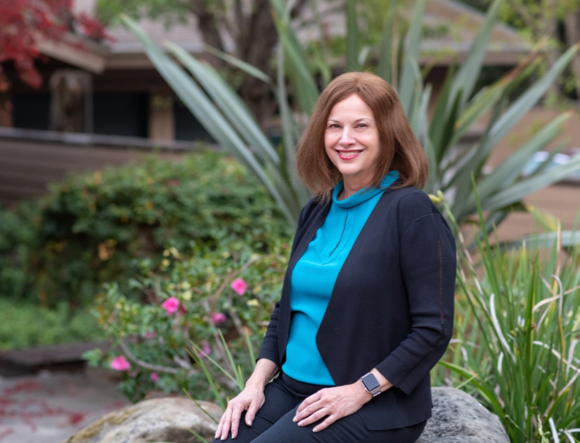Trish Costello seated outdoors beside a garden