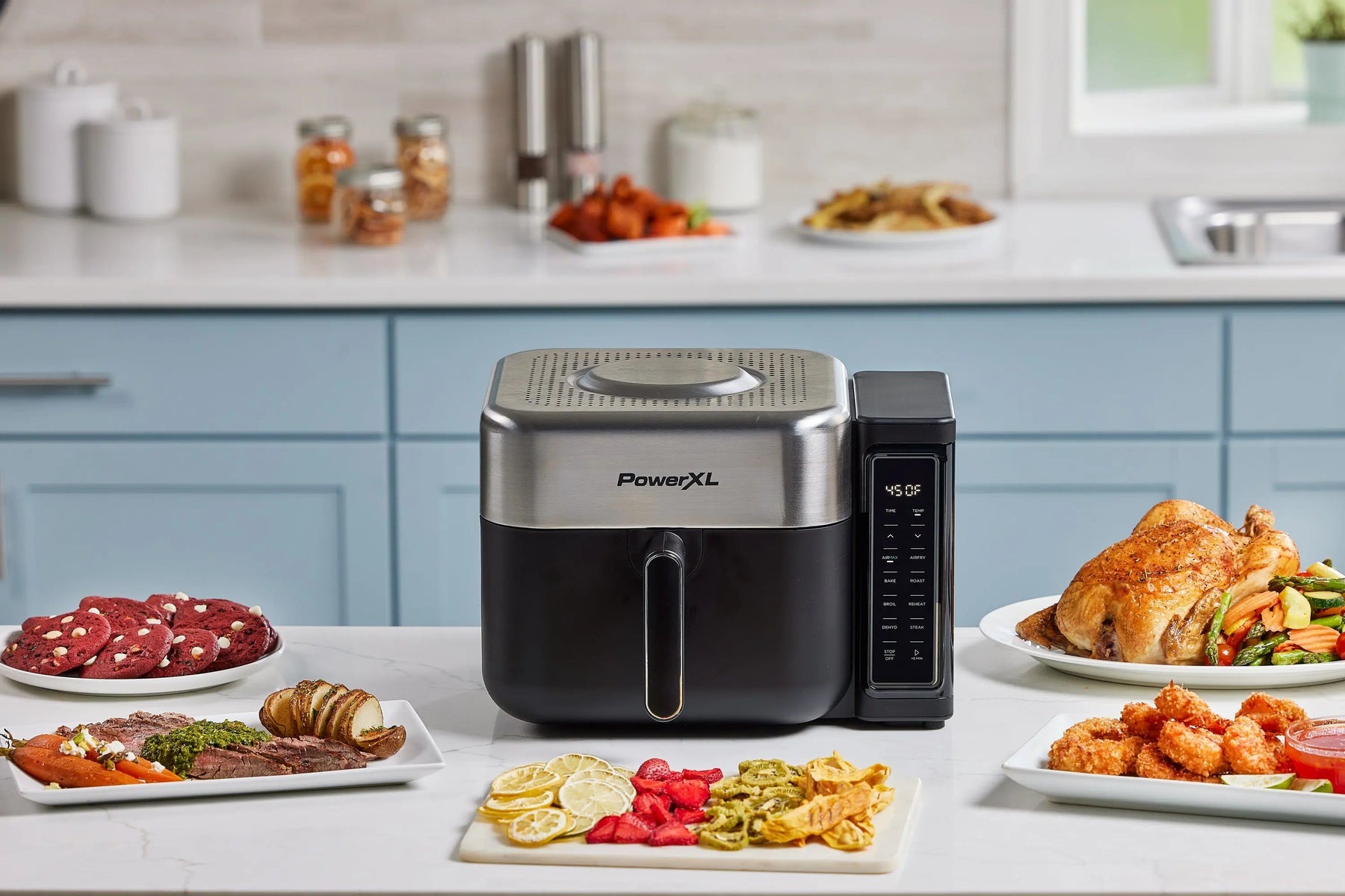 A PowerXL AIRMAX air fryer on a kitchen counter beside prepared food