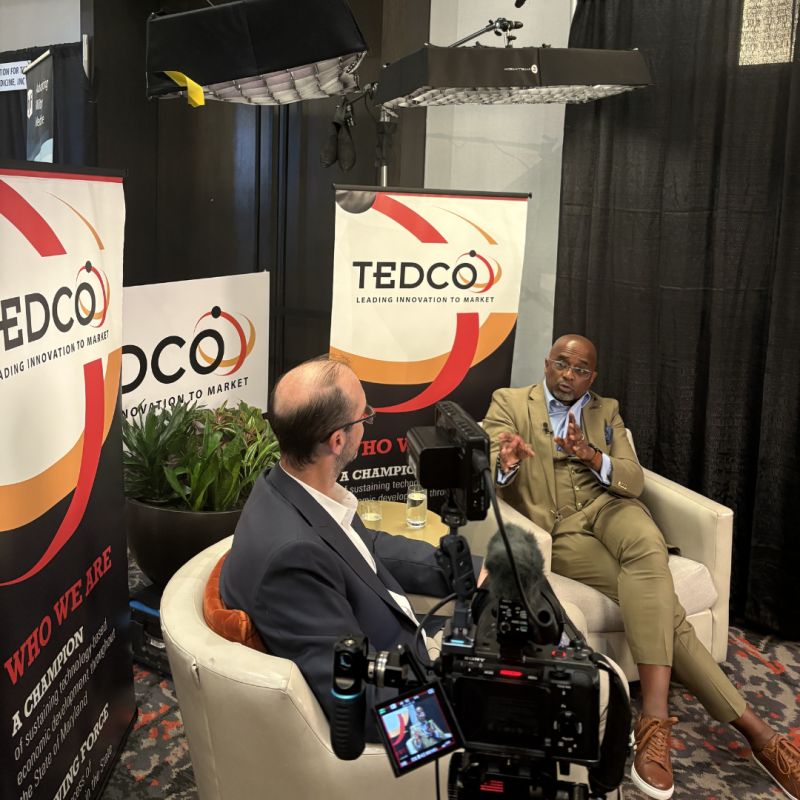 Troy LeMaile-Stovall seated at right, speaking with Chris Frew during a filmed TEDCO Expo interview