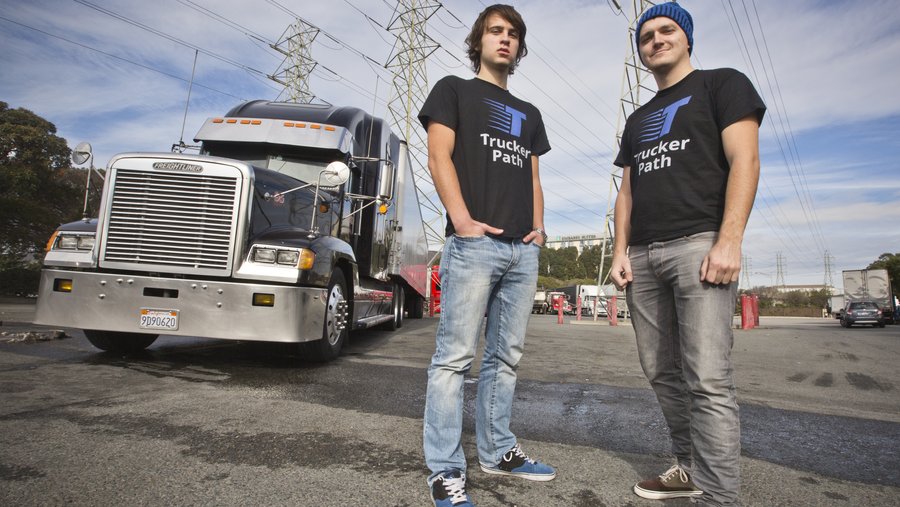 Trucker Path co-founders Viktor Radchenko and Ivan Tsybaev standing beside a semi-truck