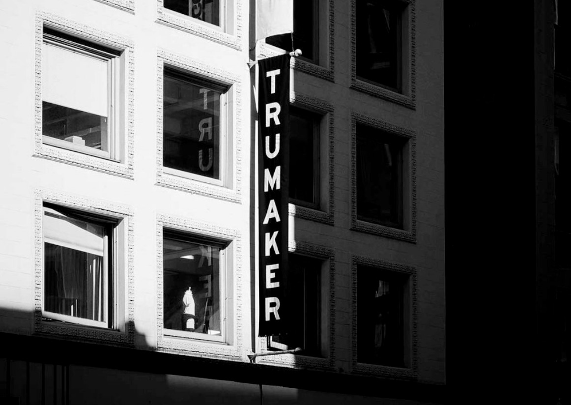 Black-and-white photograph of a Trumaker sign on a city building