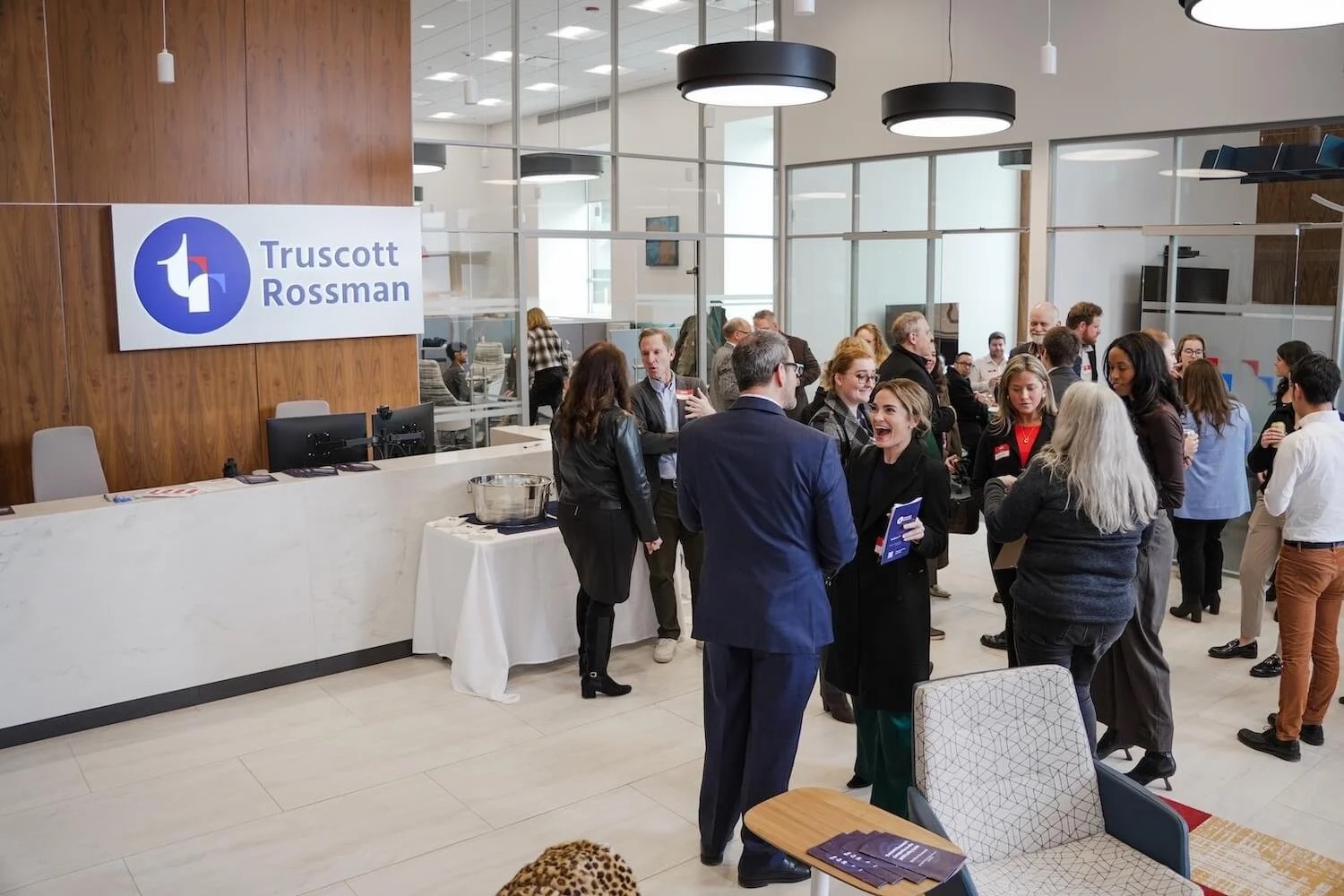 People talking inside a bright Truscott Rossman office