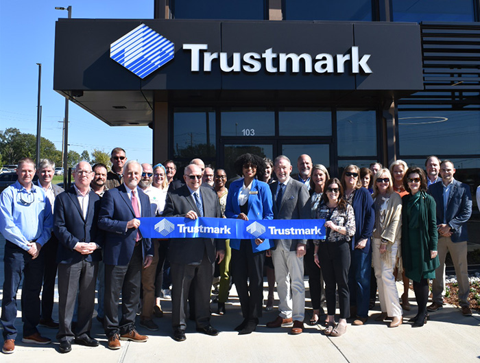 A group gathers outside a Trustmark branch for a ribbon-cutting ceremony
