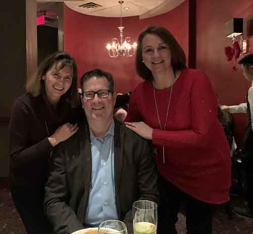 Three members of the TSN Communications team smiling together at dinner