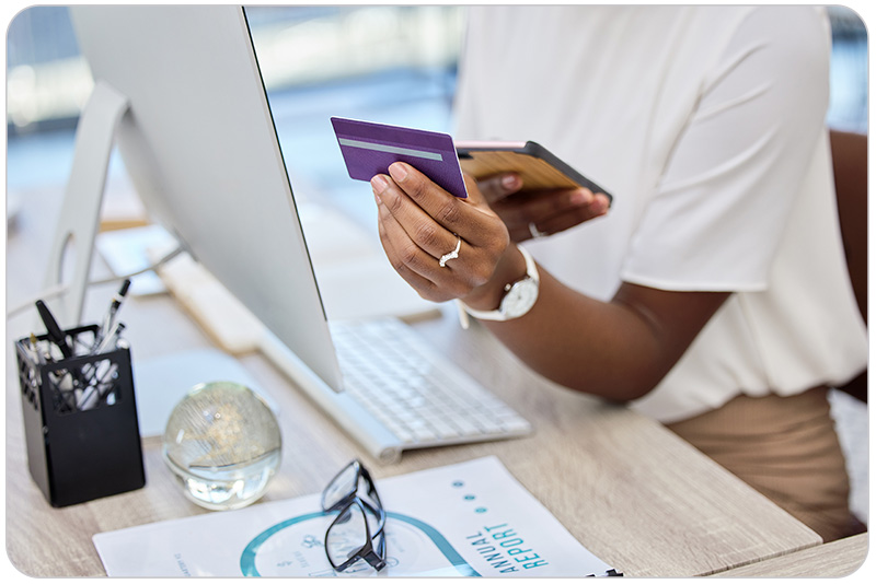 Tuition.io promotional photograph showing a person holding a payment card beside a computer