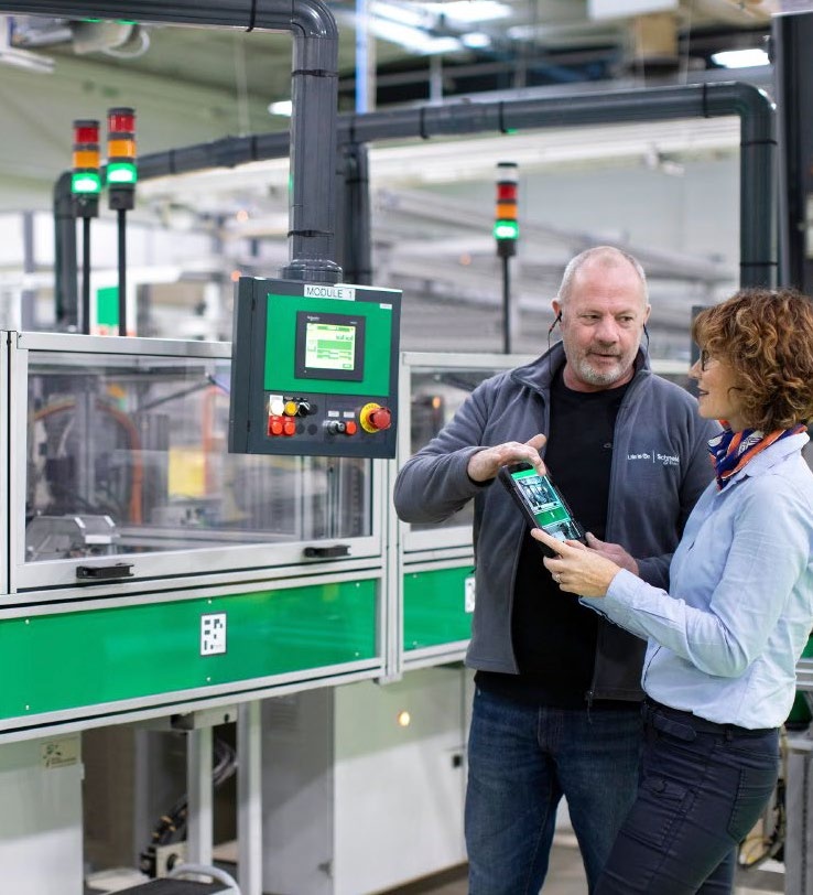 Two people examine a tablet beside industrial equipment in a Schneider Electric case study photograph
