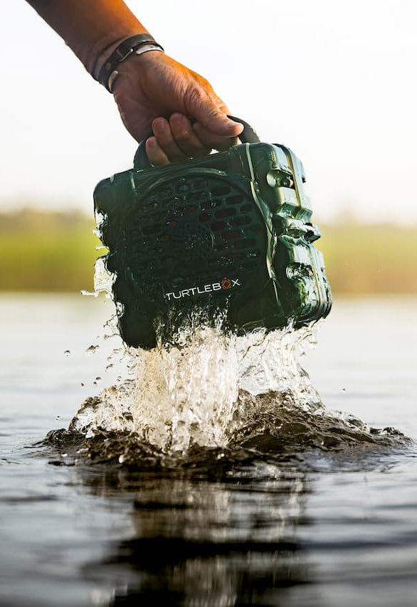 Turtlebox Cub speaker in green on a paddleboard