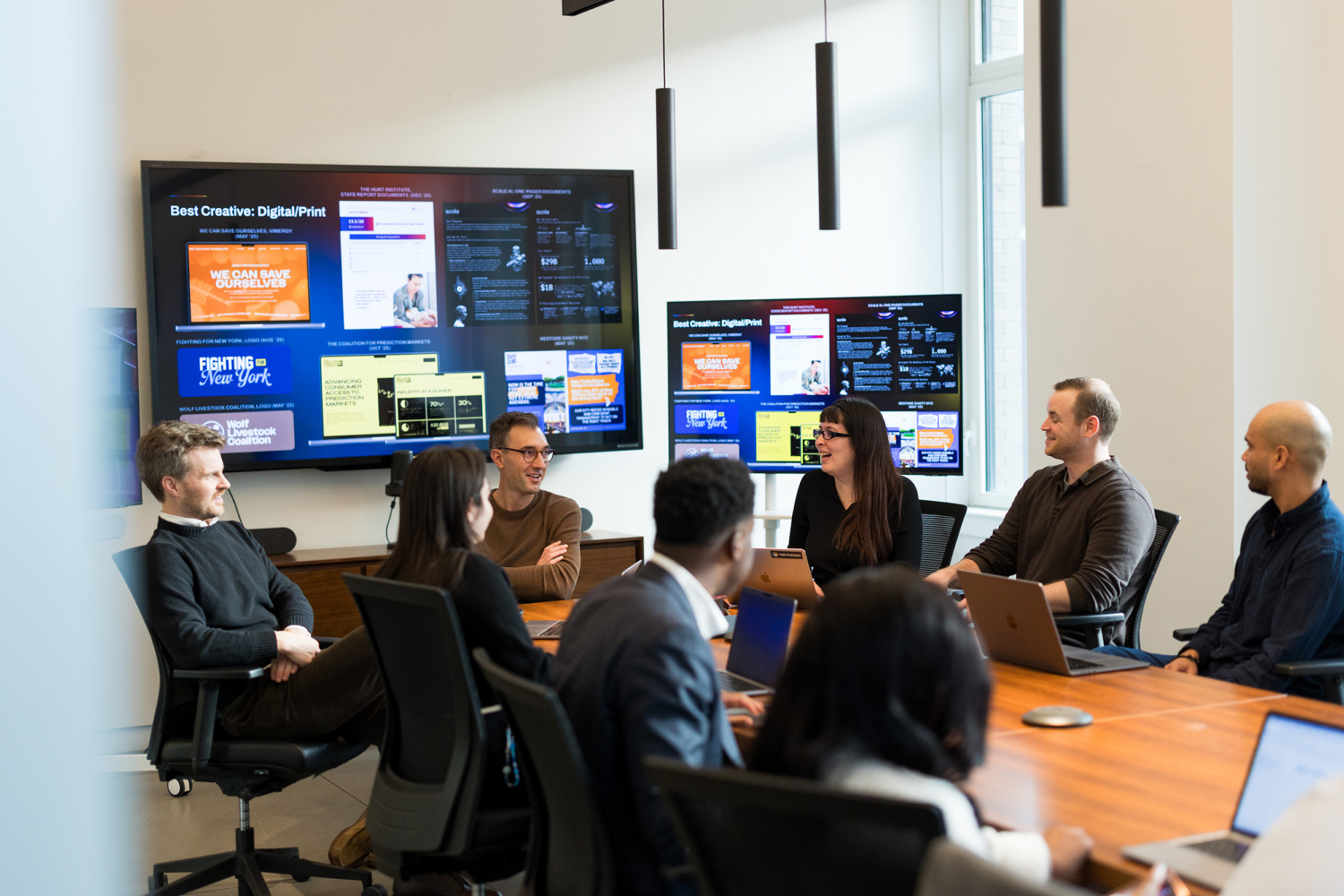 Tusk Strategies team members in a conference room with campaign creative displayed on screens