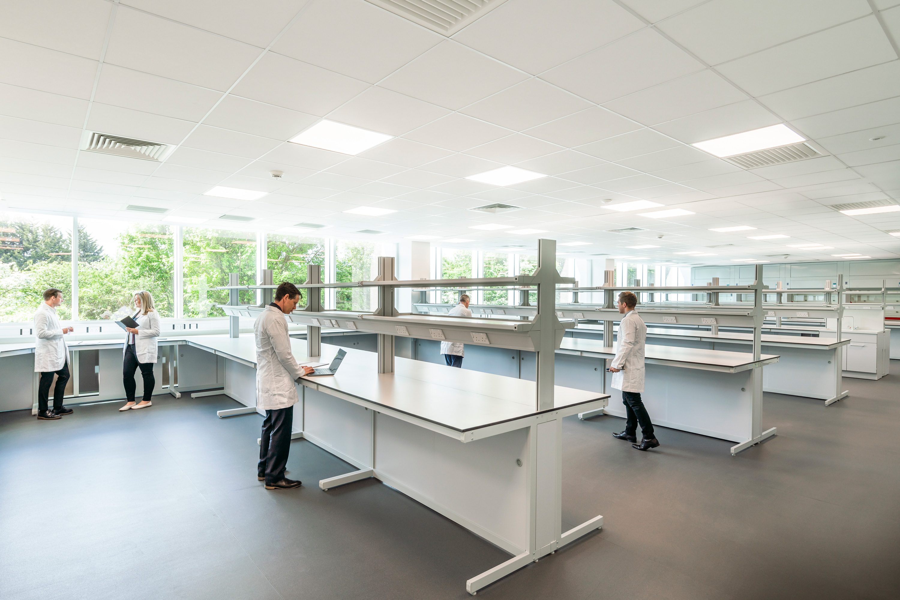 People in white laboratory coats among rows of benches at TusPark Cambridge