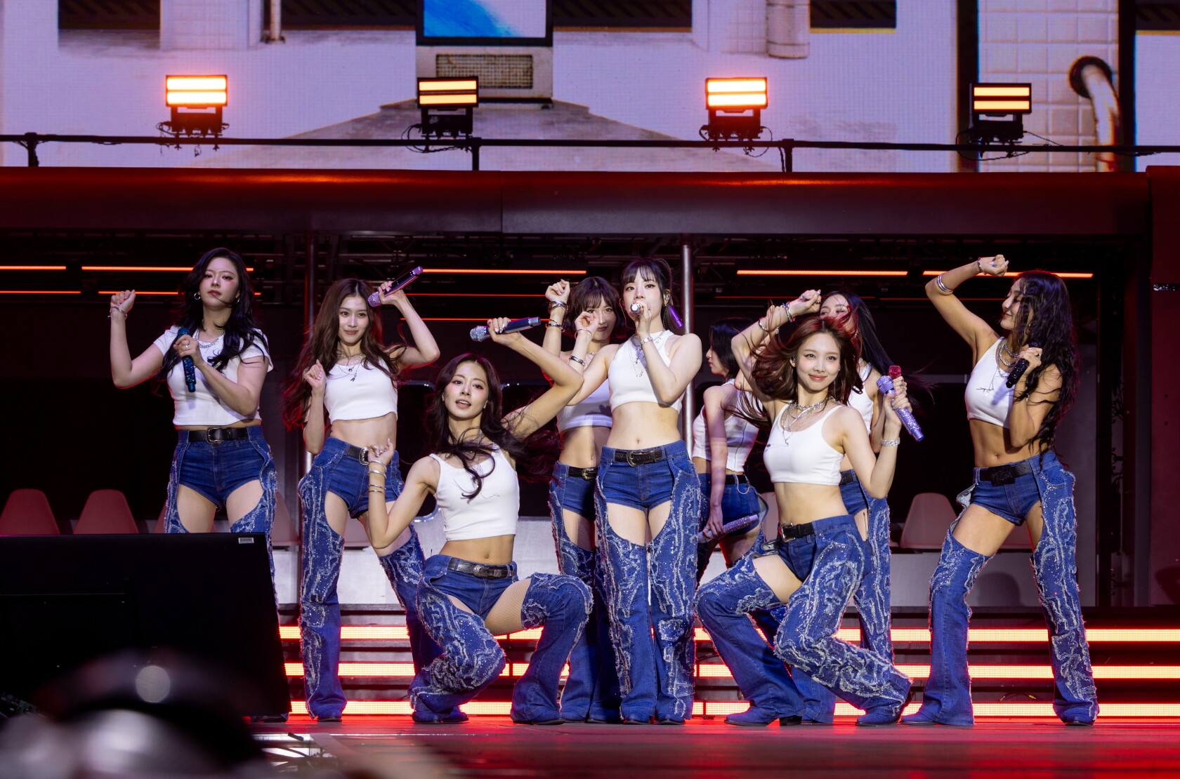 The nine members of TWICE perform in coordinated white and denim looks at Lollapalooza Chicago in 2025
