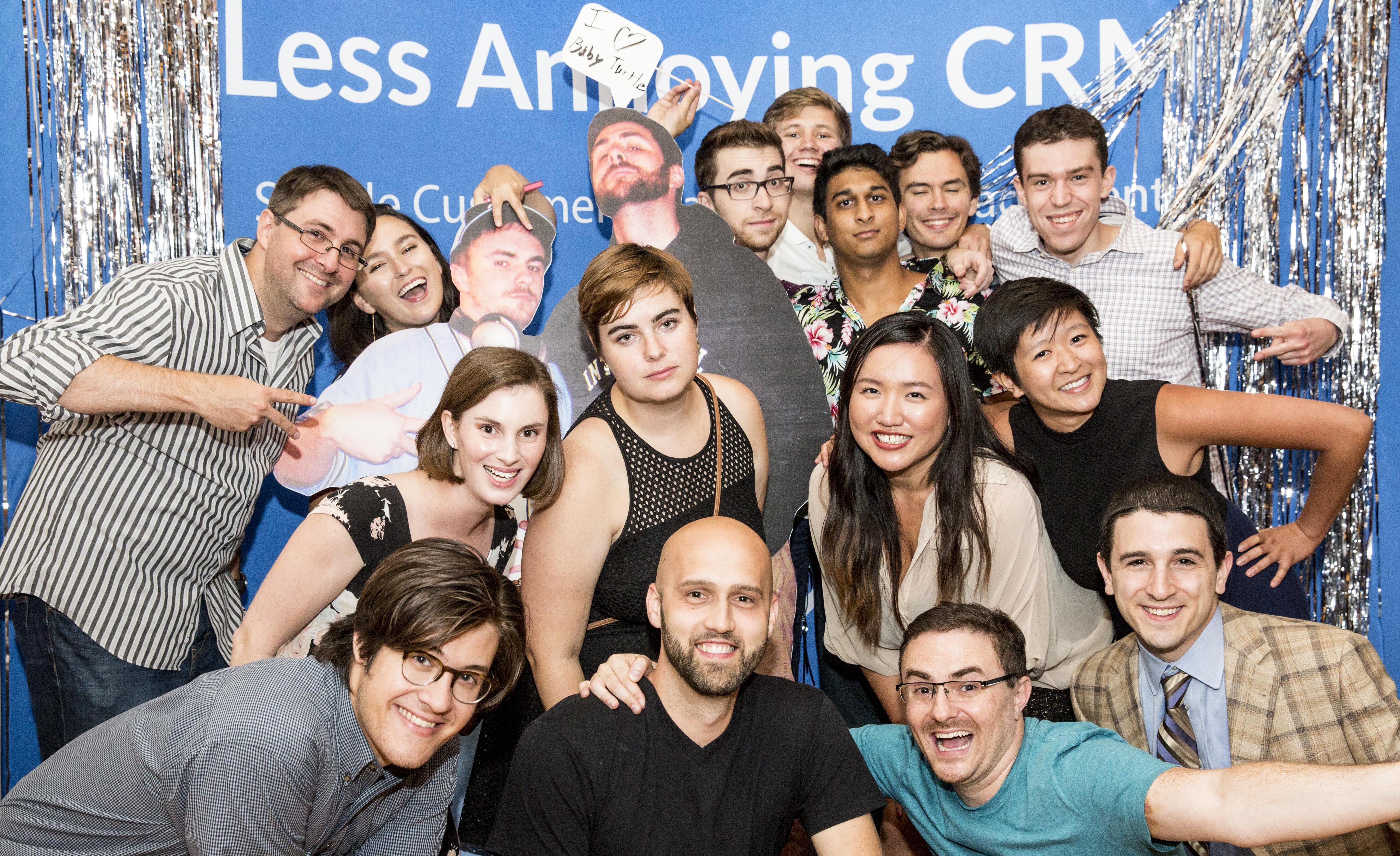 The Less Annoying CRM team celebrating its 10,000-user milestone with silver decorations and playful photo props