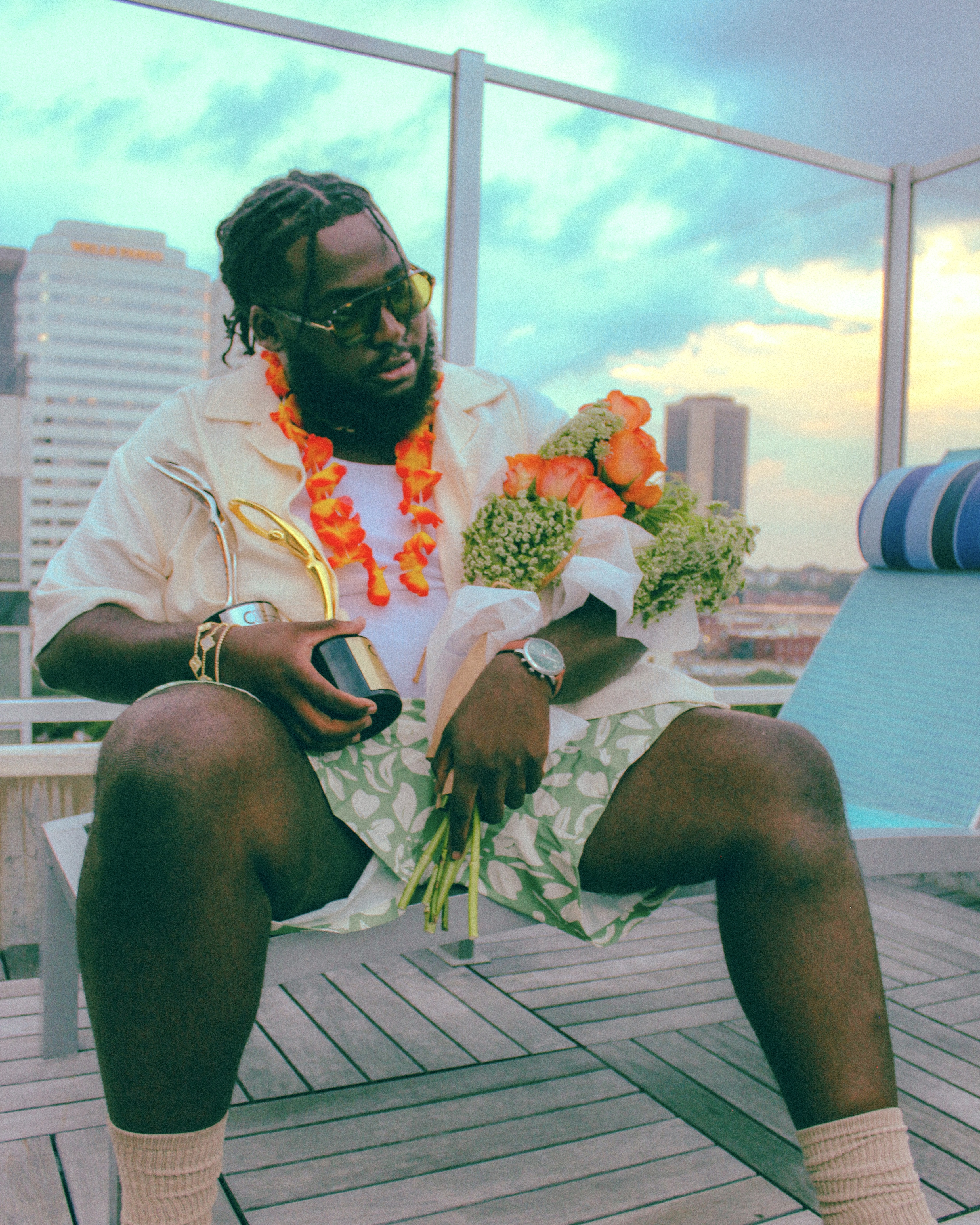 Tyrone Nelson Jr. seated outdoors, holding flowers and a trophy