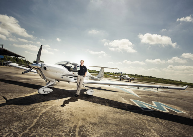 Tyson Weihs standing beside a light aircraft on an airport apron