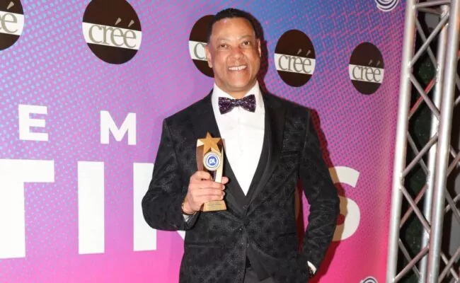 Ubaldo Torres in a black tuxedo and bow tie holding a star-shaped award