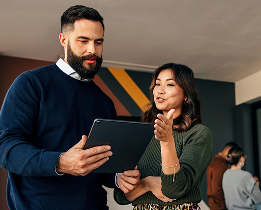 Two people reviewing a tablet in an office, in an illustrative image used by Ubiquity
