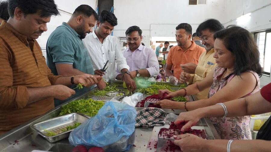 Training participants prepare leafy vegetables and beetroot around a worktable