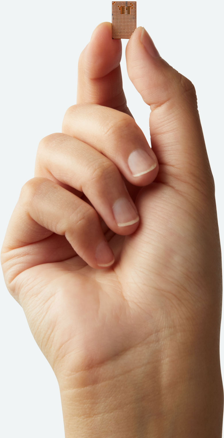 Uhnder radar chip held upright between a thumb and fingertip