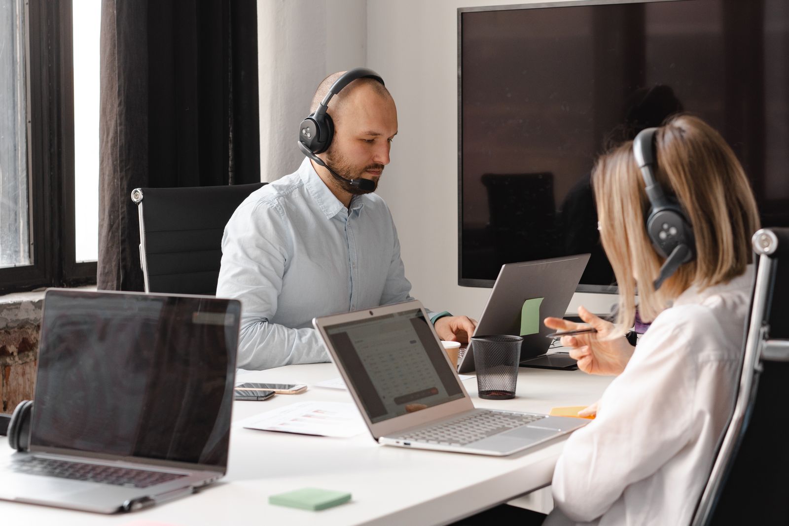 Customer support agents collaborating with laptops and headsets in an office