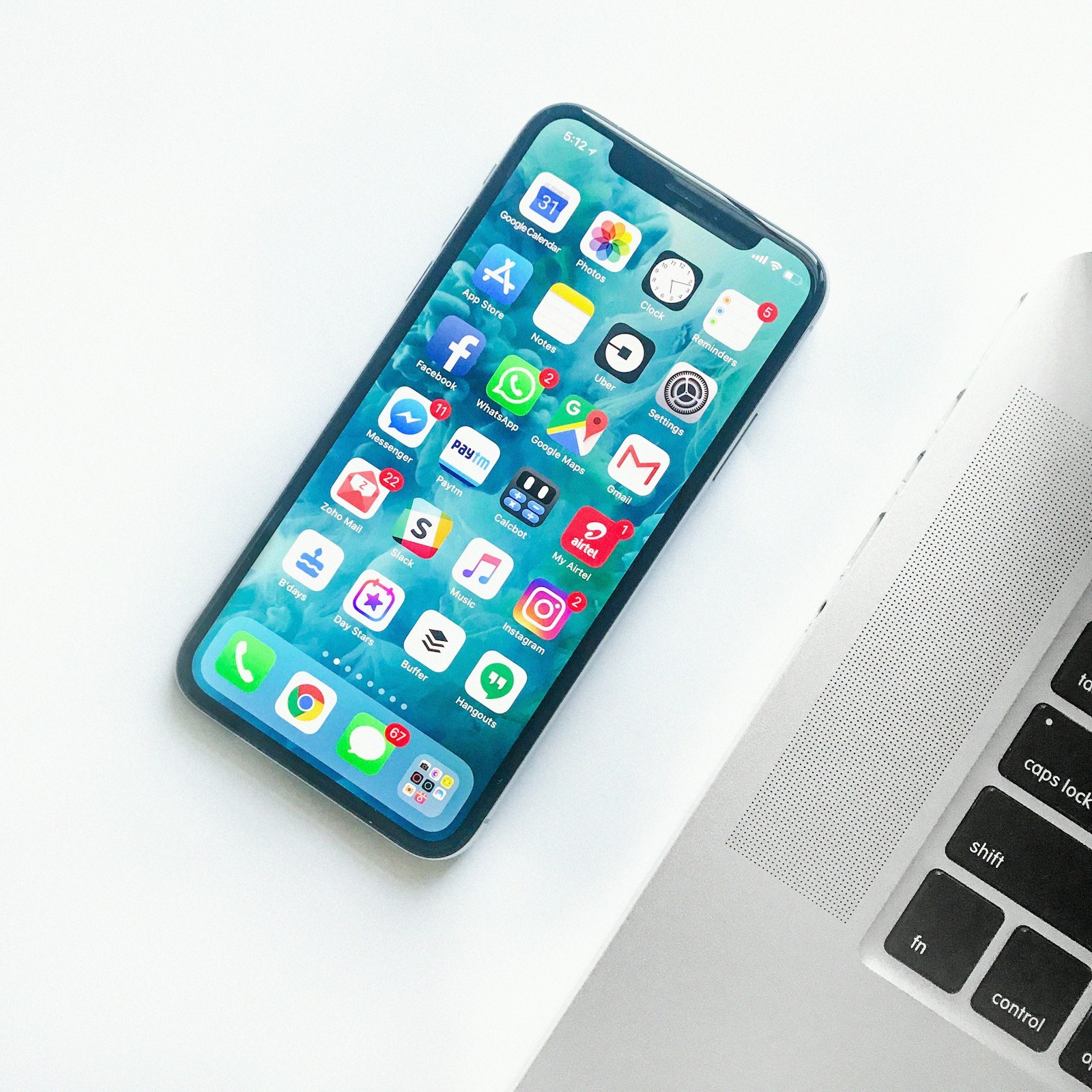 An iPhone showing app icons beside a laptop