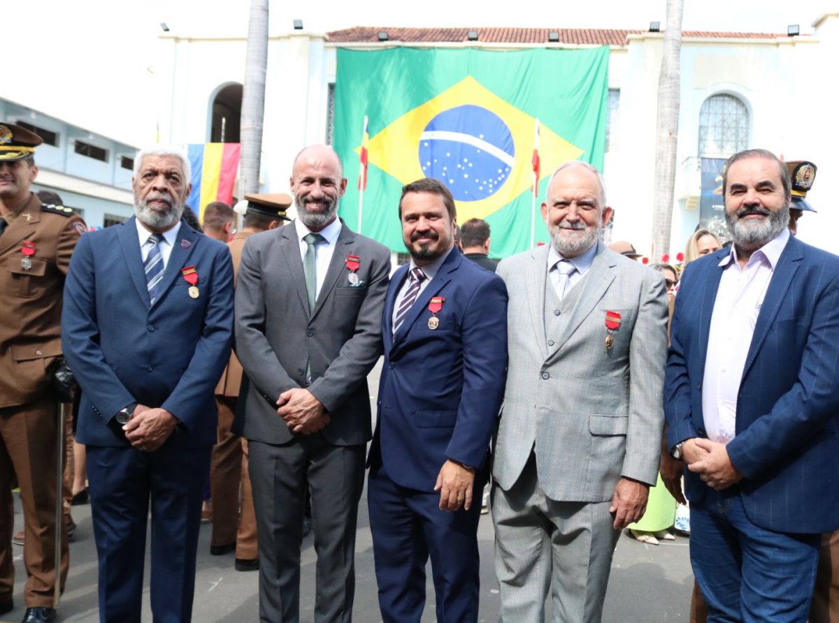 Medal recipients standing before a large Brazilian flag at a 2025 veteran ceremony