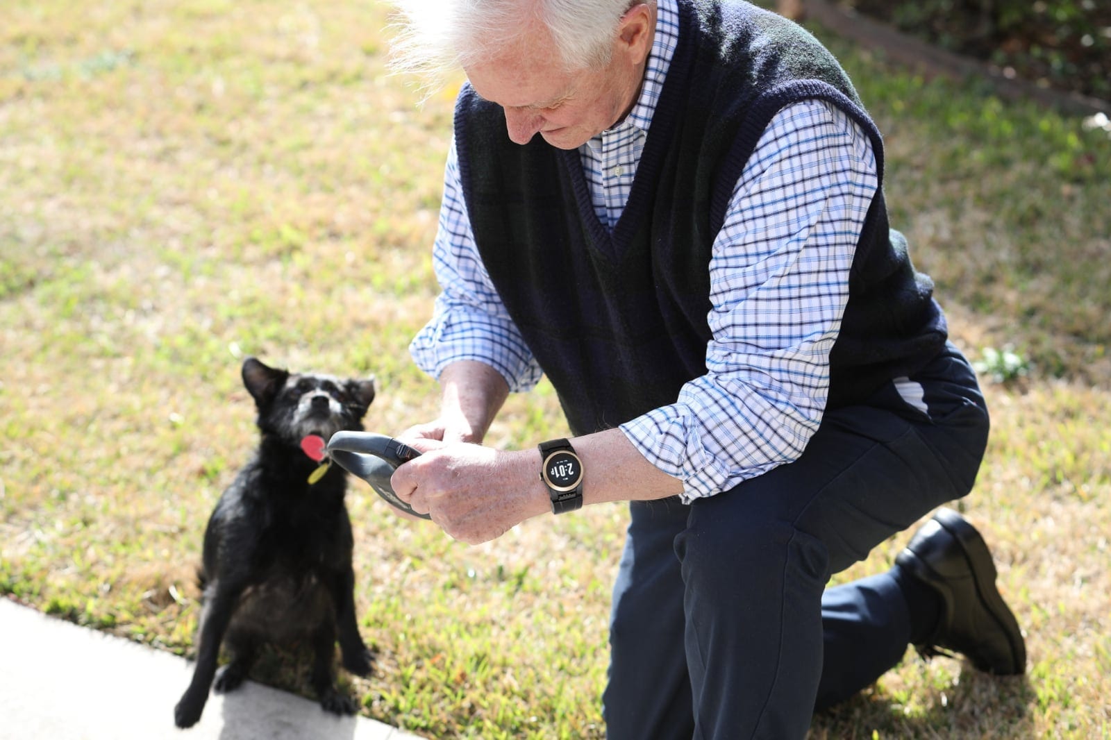 An older adult wearing the Kanega Watch outdoors with a dog