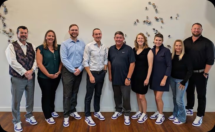 Momentus leadership group pictured together in matching purple sneakers