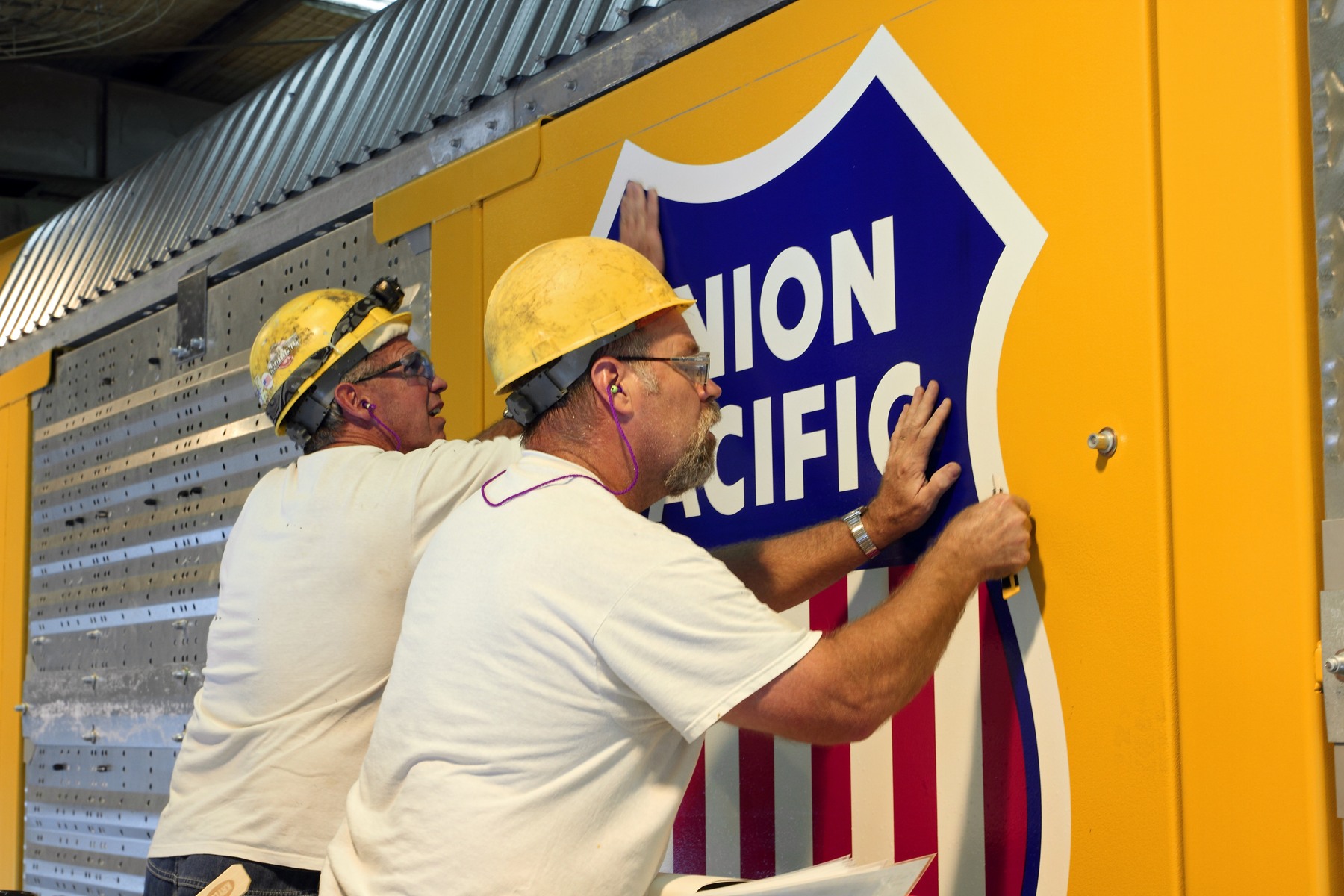Union Pacific employees Jeff Davis and Rick Bowen applying decals to an Auto Flex railcar at DeSoto Car Shop in Missouri