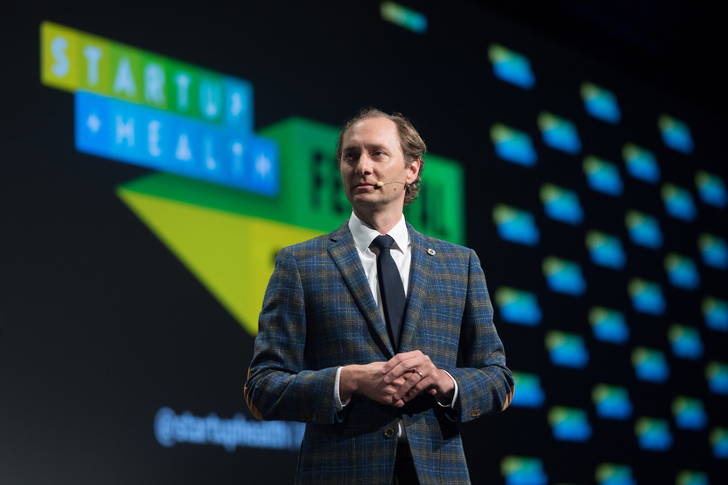 Unity Stoakes onstage wearing a checked jacket and headset microphone