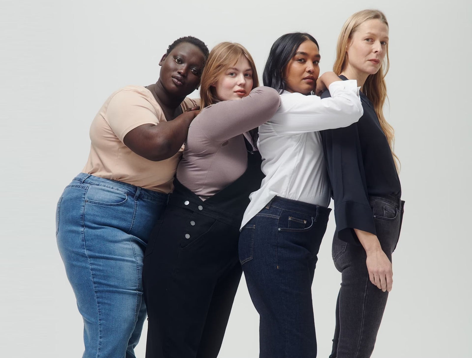 Four Universal Standard campaign models wearing denim and neutral tops