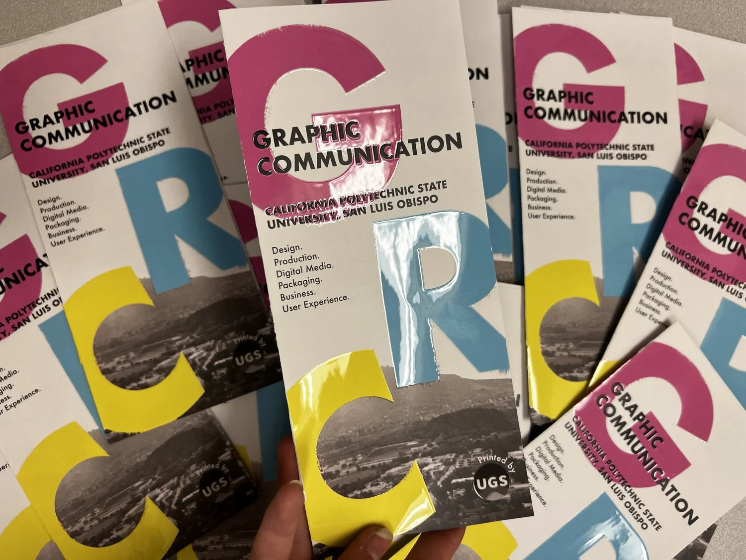 Glossy Graphic Communication brochures printed in bright pink, blue and yellow