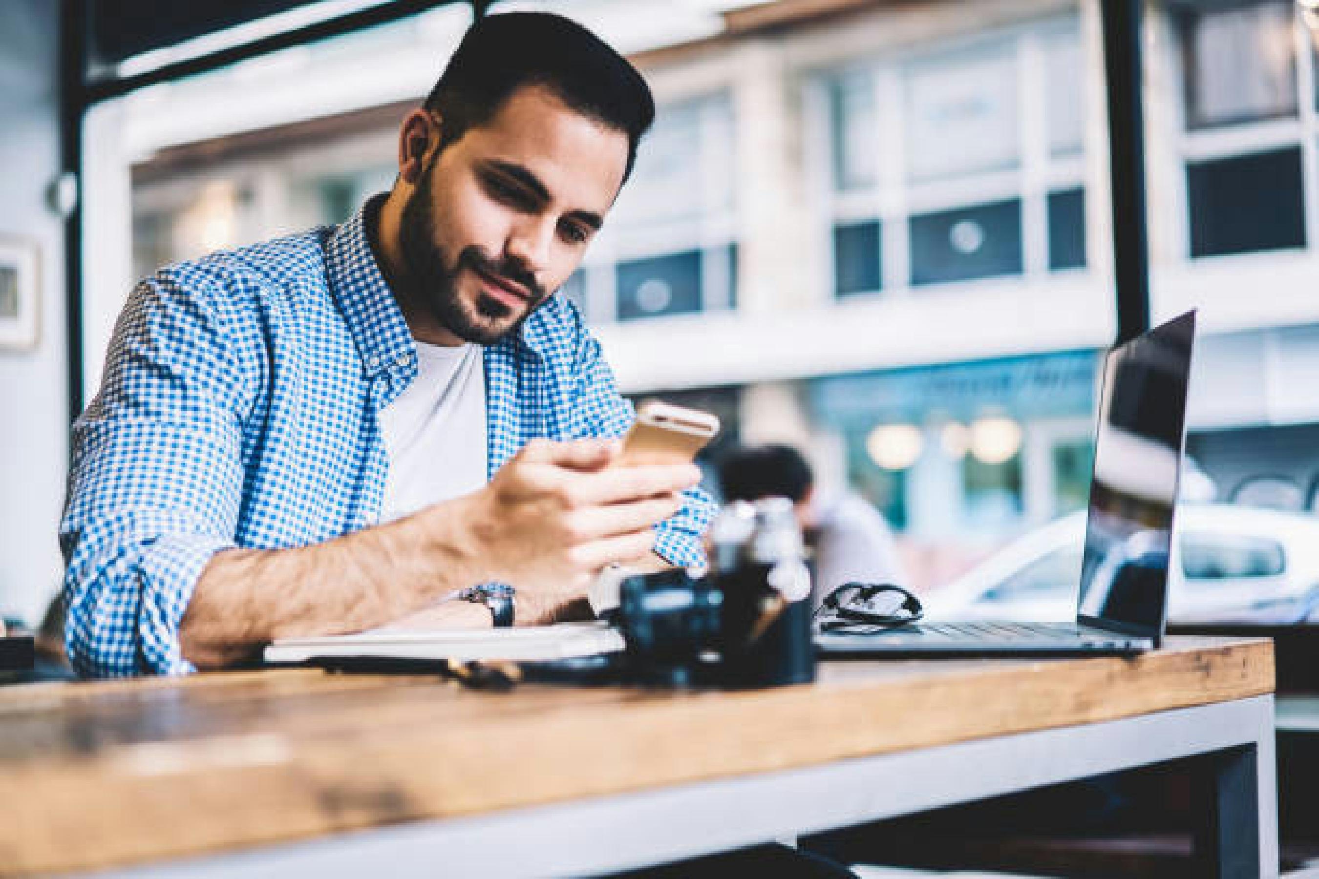 Promotional photograph distributed with the 2022 Martti Translation launch, showing a person using a phone beside a laptop