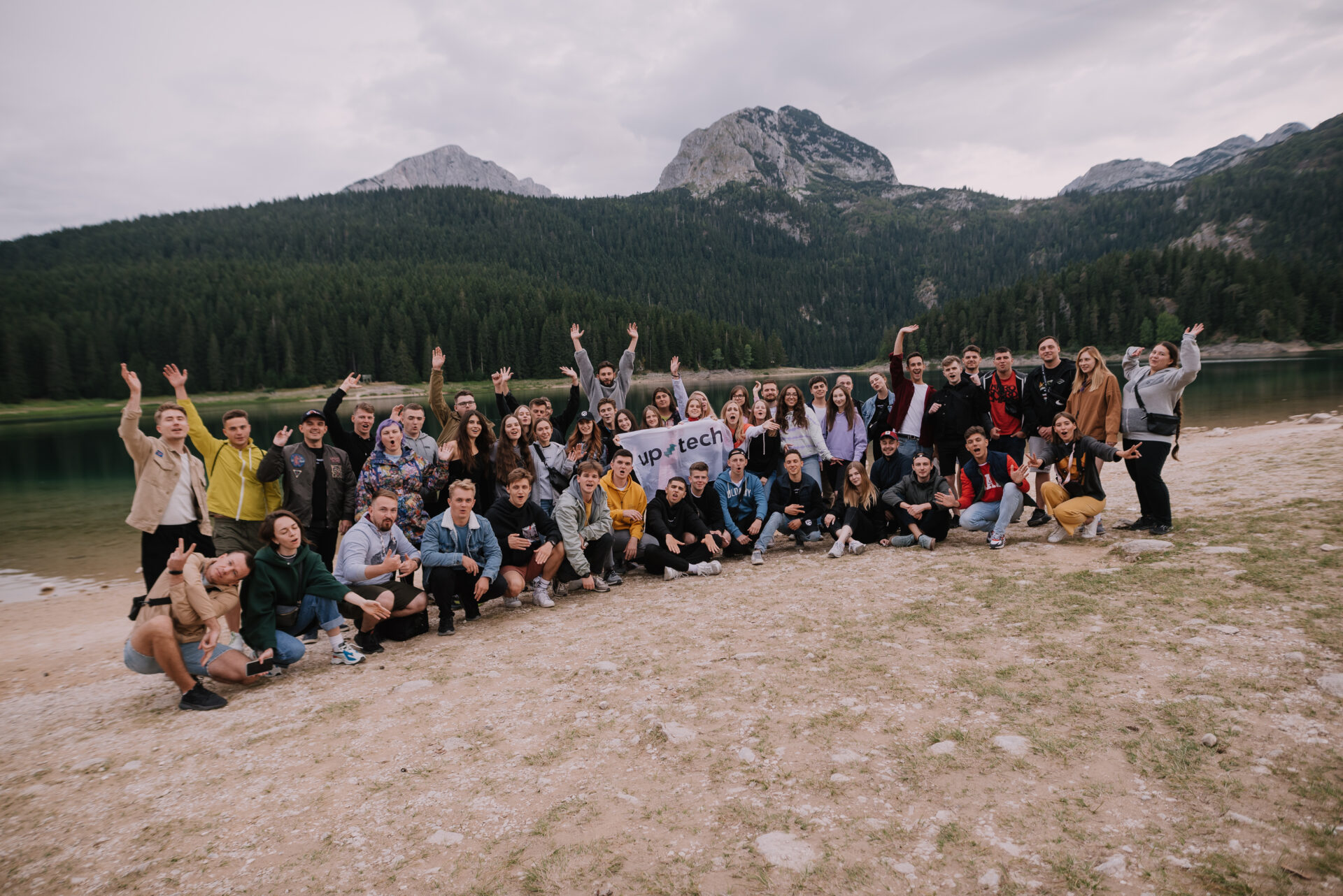 Uptech team gathered beside a lake with mountains behind them