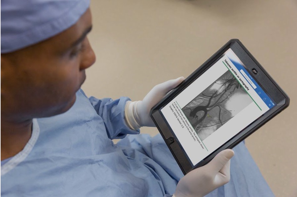 Clinician in surgical clothing viewing an UpToDate medical image on a tablet