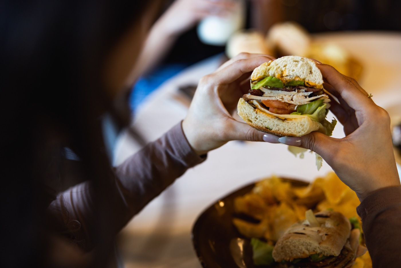 Close-up of a diner holding a layered Urban Plates sandwich