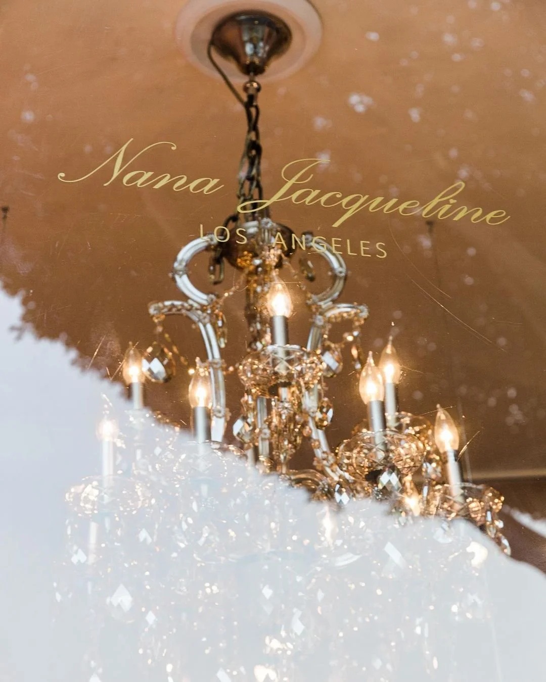 Nana Jacqueline Los Angeles lettering on a window with a chandelier visible behind the glass